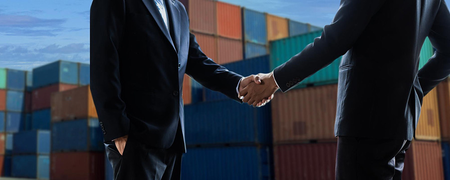 Handshake in front of stacked shipping containers